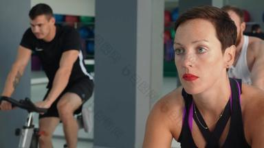 美丽的女人培训骑自行车类健身房肖像健身女人培训室内自行车自行车健身房体育运动女人旋转自行车集团培训